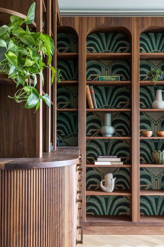 a wooden bookcase filled with lots of books next to a potted green plant