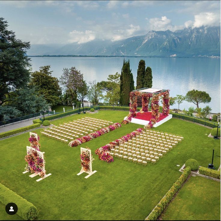 an outdoor ceremony setup with chairs and flowers on the lawn, overlooking water in the background