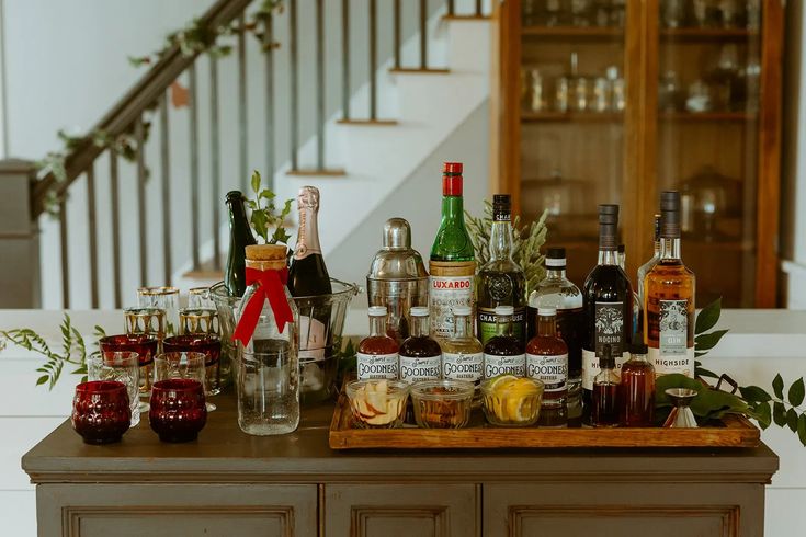 a wooden table topped with lots of bottles and glasses next to a bannister