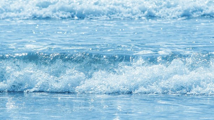 a person riding a surfboard on top of a wave in the ocean with blue water