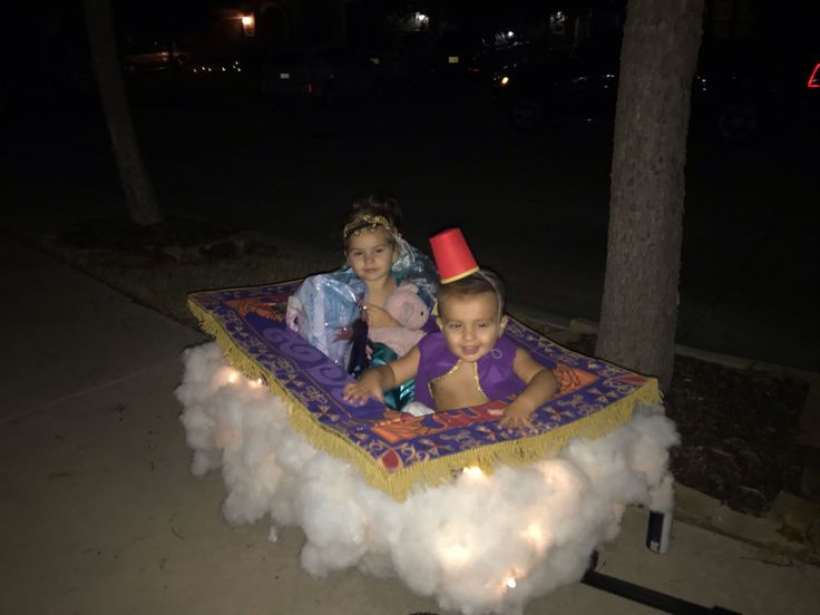 two young children sitting on top of a float in the middle of a street at night