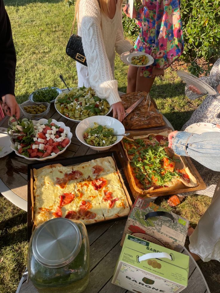 a group of people standing around a table filled with food