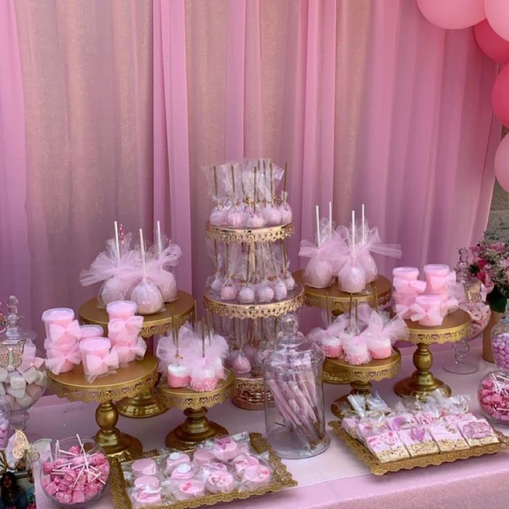 a table topped with lots of pink and gold desserts