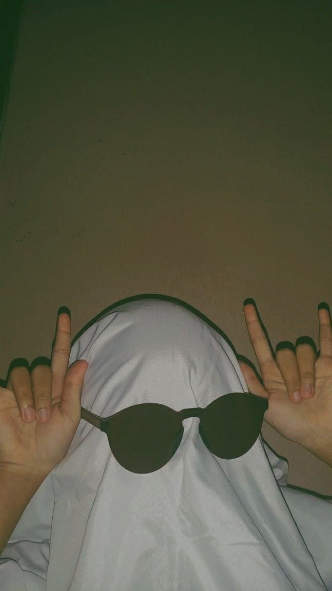 a person wearing sunglasses covering their face with one hand and two fingers in the air