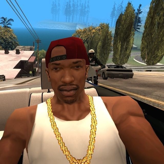 a man in a white tank top and red cap with a gold chain on his neck