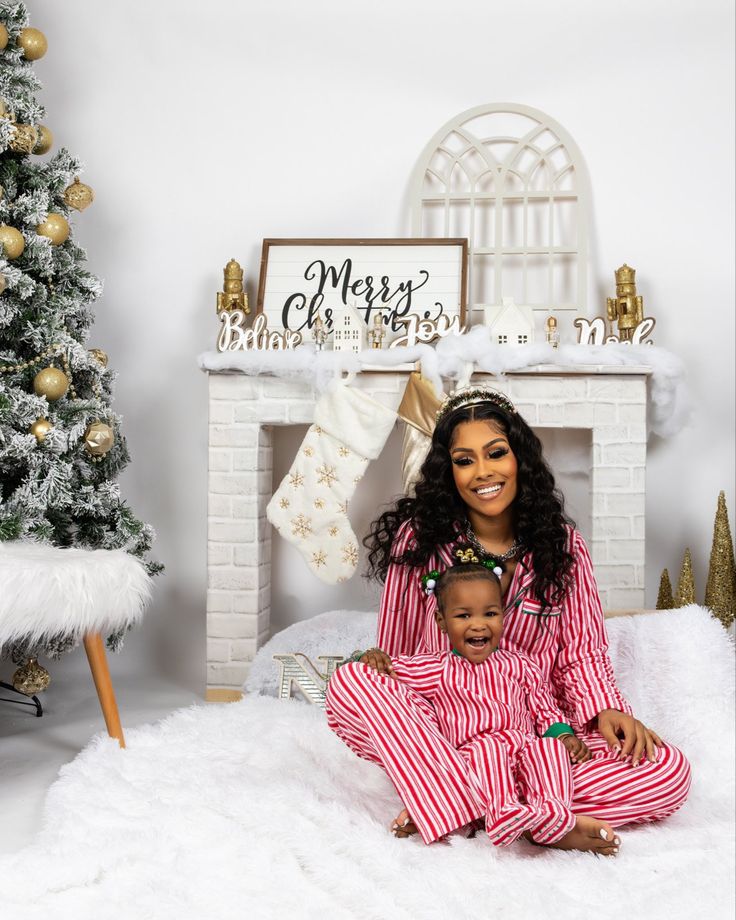 a woman and child sitting in front of a christmas tree