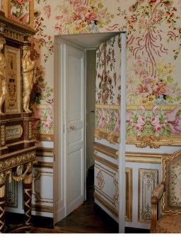 an ornately decorated room with floral wallpaper and gilded furniture, including a mirror