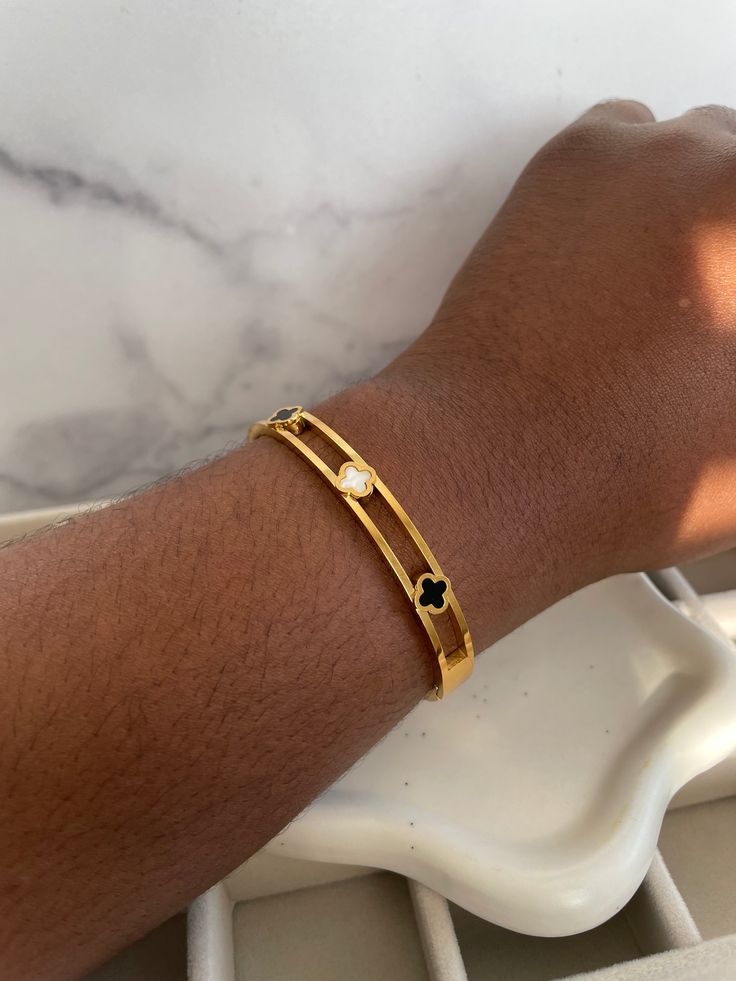 ✨Elevate your elegance with this stunning double-band gold bangle, a masterpiece of modern luxury. ✨Adorned with delicate quatrefoil motifs in glossy black and mother-of-pearl enamel, this piece is a celebration of contrast and refinement. ✨The open design creates a sense of lightness while still making a bold statement, ensuring every movement catches the eye. ✨Perfect for layering or wearing solo, this bangle is your new go-to for a chic yet daring look. ✨A sophisticated accessory that effortl Elegant Black Enamel Bangle For Gift, Elegant Black Enamel Bangle Gift, Luxury Gold Bangle With Black Enamel, Elegant Black Enamel Bangle, Gold Bangle, Open Design, Gold Bangles, Gold Bands, Ring Necklace