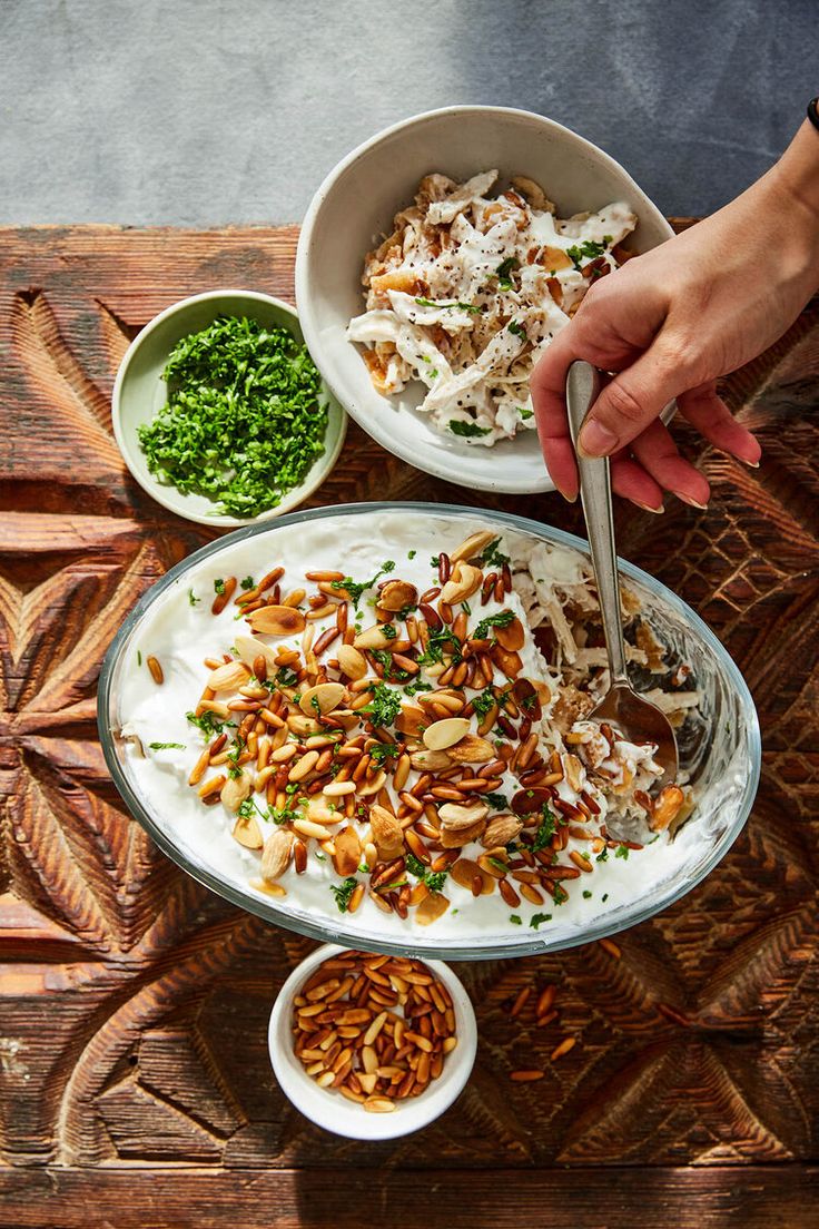 a person is eating food out of a bowl on a wooden table with other bowls