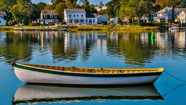 a small boat floating on top of a lake next to houses in the background,