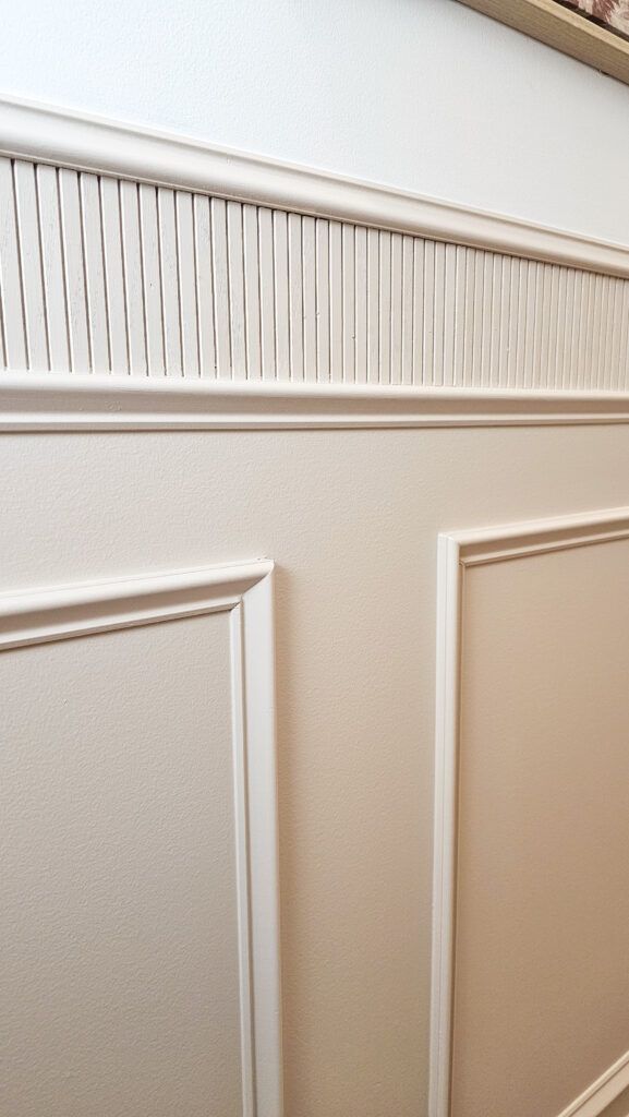 a white toilet sitting in a bathroom next to a wooden wall with paneling on it