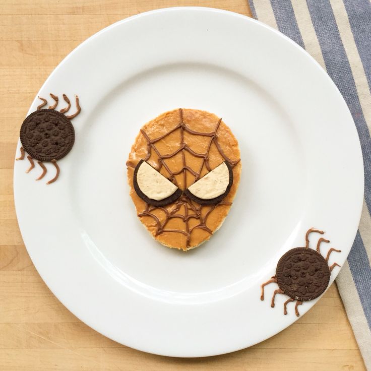 a white plate topped with pancakes covered in peanut butter and spider webs