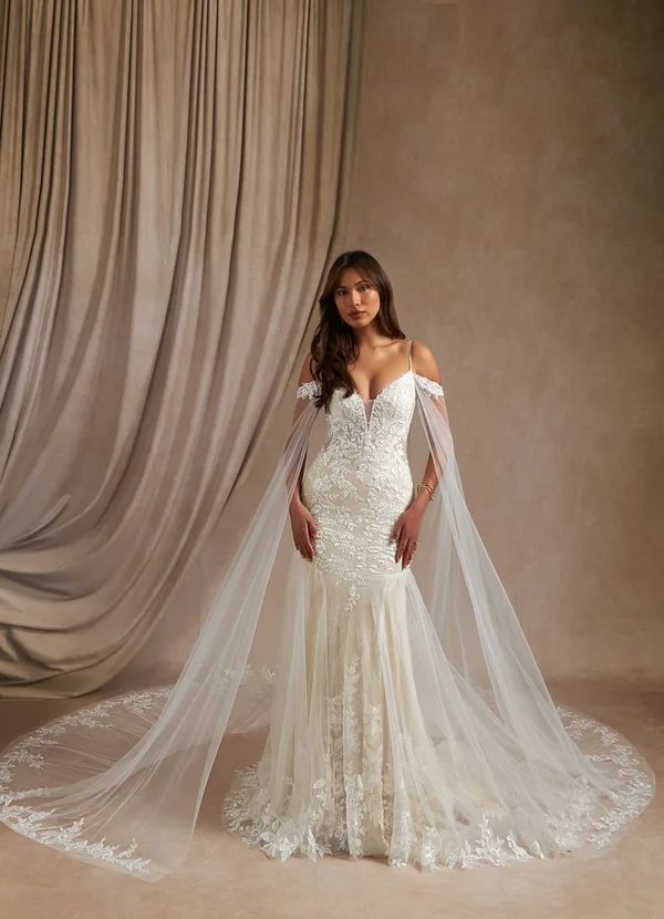 a woman in a wedding dress with a veil on her head standing next to a curtain