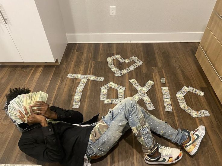 a man laying on the floor with money in his hands