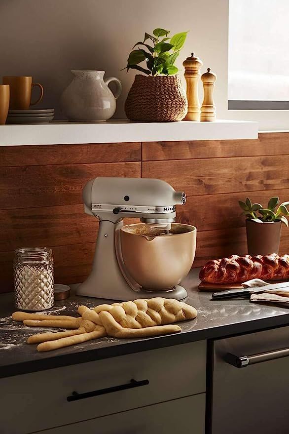 a kitchen counter topped with lots of food next to a mixer and some breadsticks