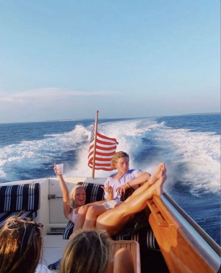 people sitting on the back of a boat with an american flag flying in the air