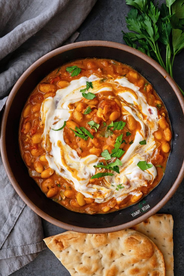 a bowl of chickpea stew with pita chips and parsley on the side