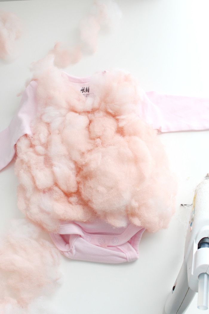 a baby's pink shirt and hair dryer on a white surface with cotton floss