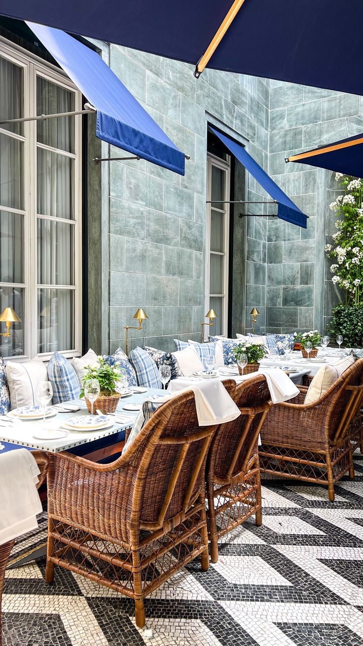 an outdoor dining area with wicker chairs and blue umbrellas