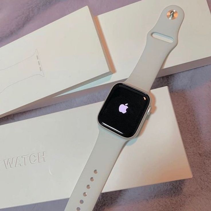 an apple watch sitting on top of a white box next to a pink and purple blanket