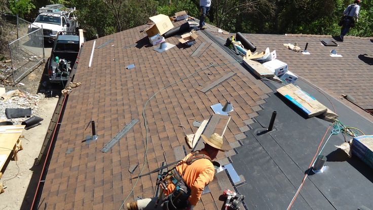 two men working on the roof of a house