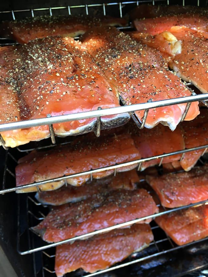 salmon cooking in an oven with seasoning on the top and bottom racks full of them