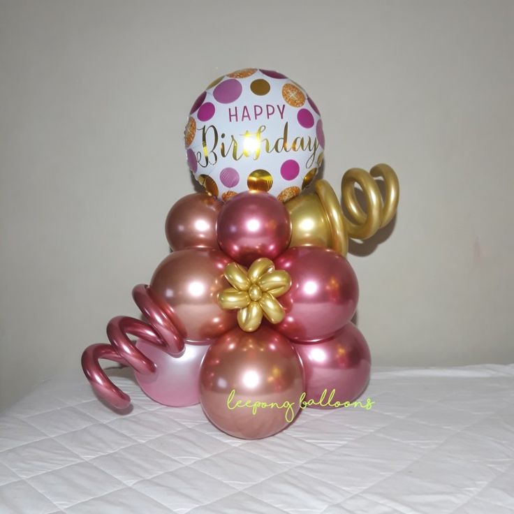 a bunch of balloons sitting on top of a bed next to a balloon with the word happy birthday