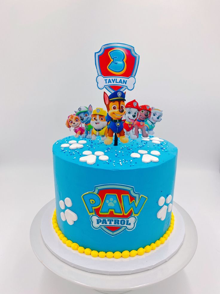 a blue cake with paw patrol characters on it