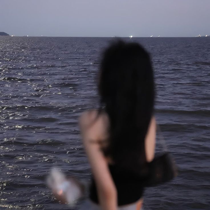 a woman standing on top of a boat in the ocean looking out at the water