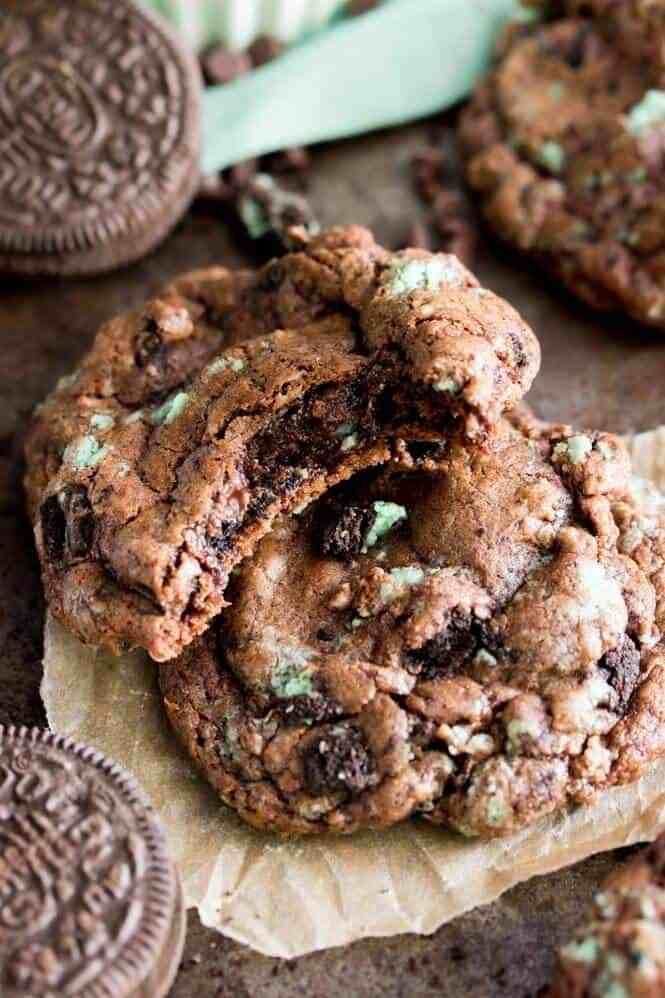 two chocolate chip cookies stacked on top of each other next to some oreo chips