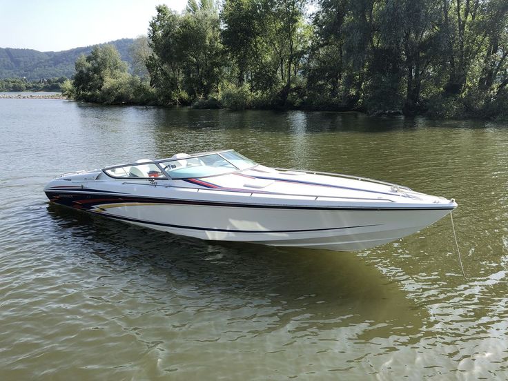 a speed boat in the water near some trees