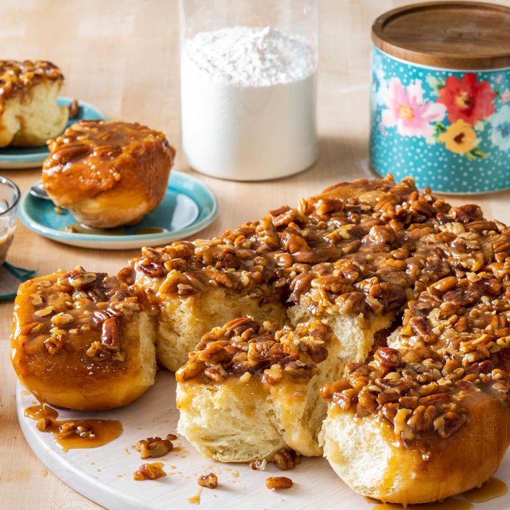 a table topped with pastries covered in pecan toppings next to a cup of coffee