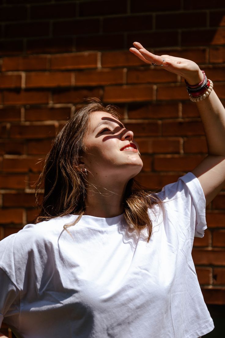 A girl with her hand up towards the sun, the shadow across her face. Hand Covering Face From Sun Pose, Covering Face From Sun Pose, Covering Eyes From Sun Pose, Looking Up Head Reference, Blocking The Sun With Hand Pose, Head Resting On Arms Pose, Hand Shielding Face From Sun Pose, Shielding Eyes From Sun Pose, Hand On Forehead Reference