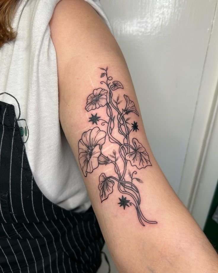 a woman's arm with flowers and vines tattooed on the left side of her arm