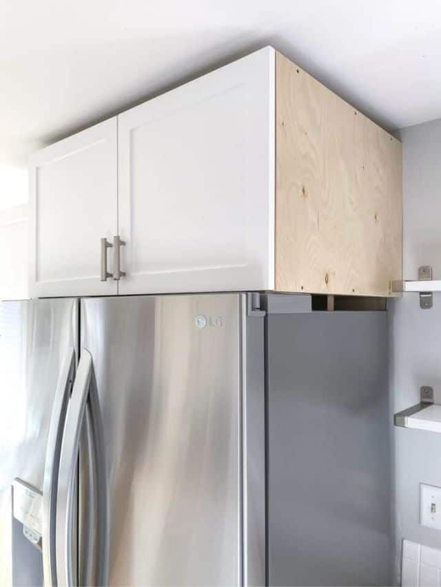 a stainless steel refrigerator in a kitchen with white cupboards and drawers on the wall