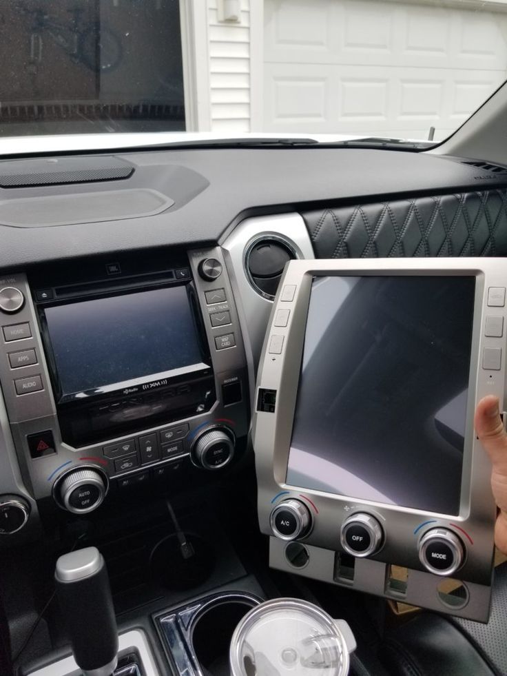 a person is sitting in the driver's seat of a car with their hand on the screen