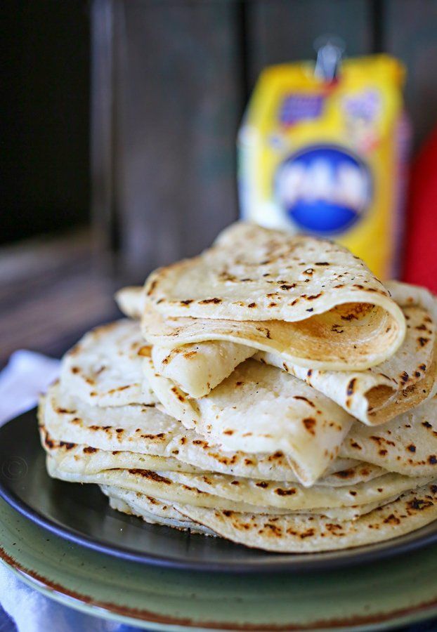 a stack of tortillas on a plate next to a carton of milk