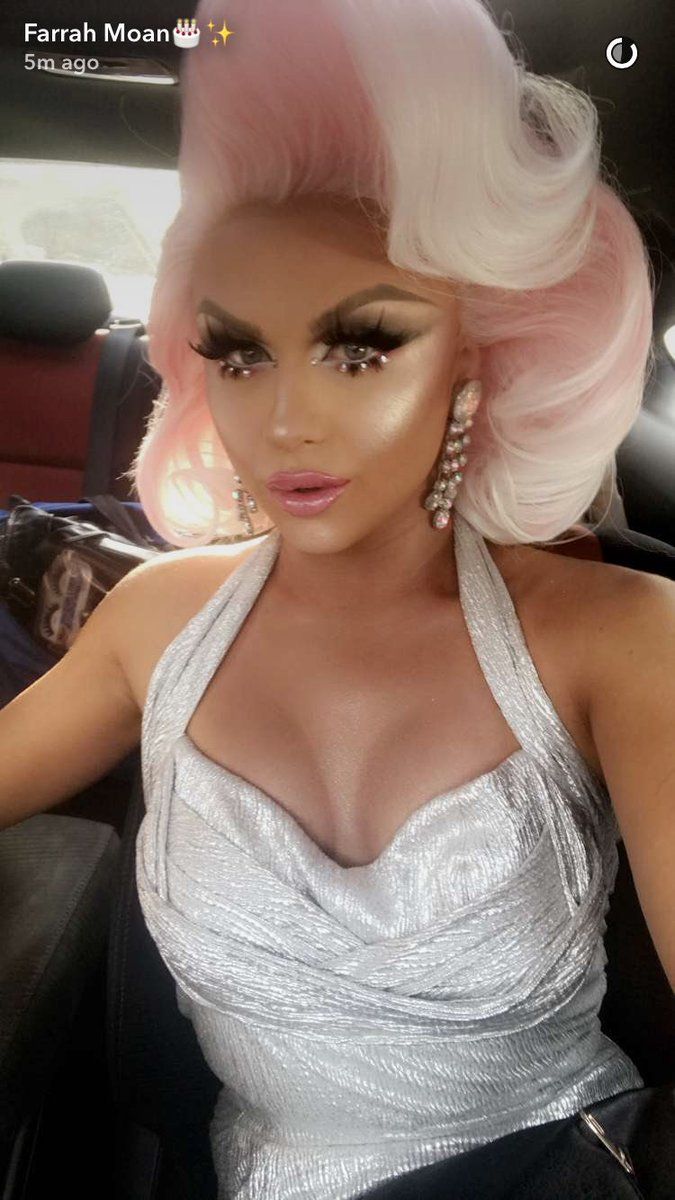 a woman with pink hair sitting in the back seat of a car wearing a silver dress