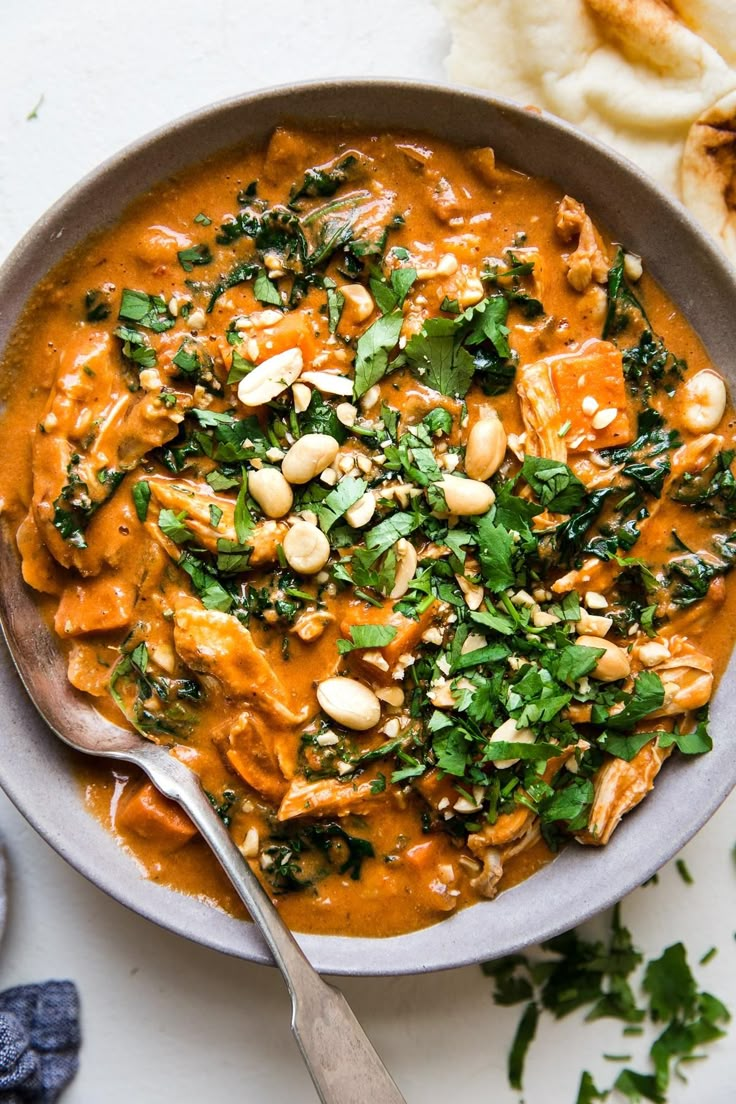 a bowl filled with soup and garnished with nuts, cilantro, and parsley