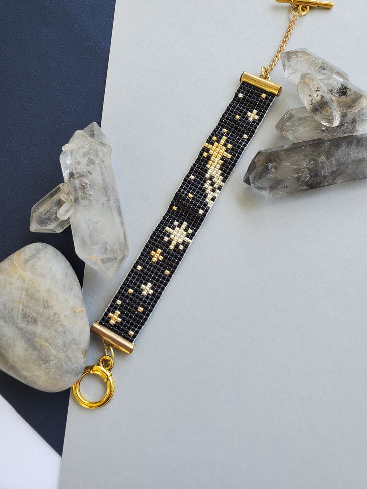 a cross beaded bracelet on a gold chain with crystal rocks and quartzs next to it