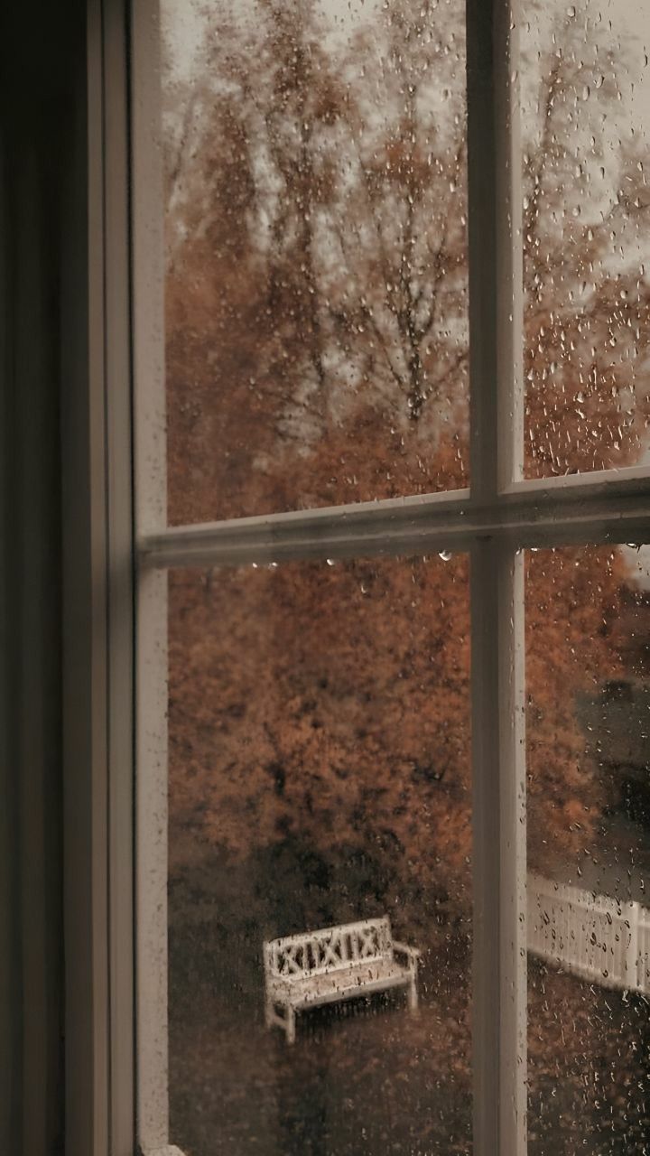 a white bench sitting next to a window covered in rain