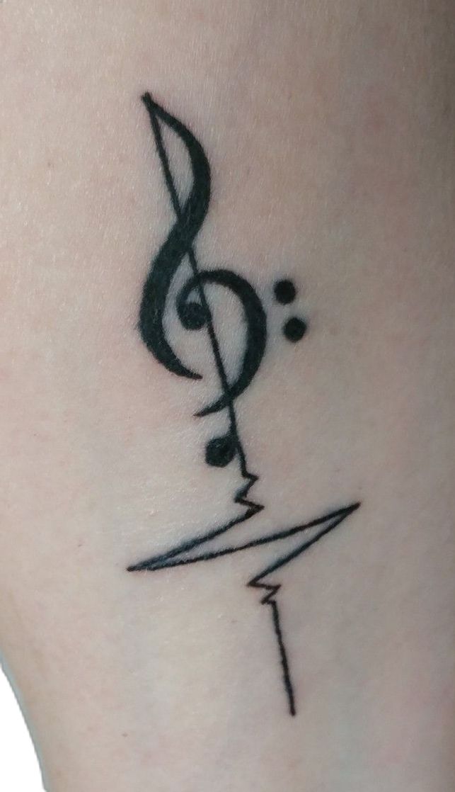 a music note tattoo on the side of a woman's leg, with a treble