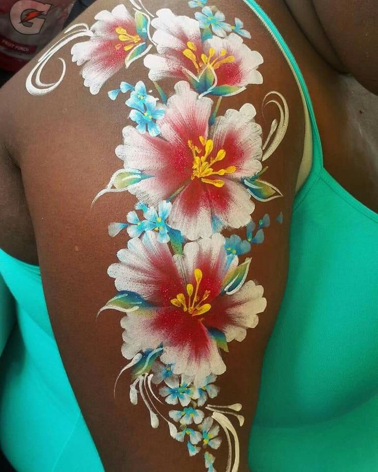 the back of a woman's shoulder with flowers painted on her arm and chest