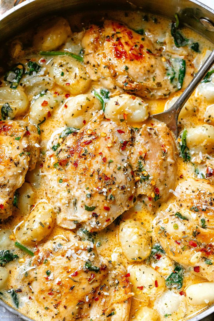 a skillet filled with chicken, potatoes and spinach