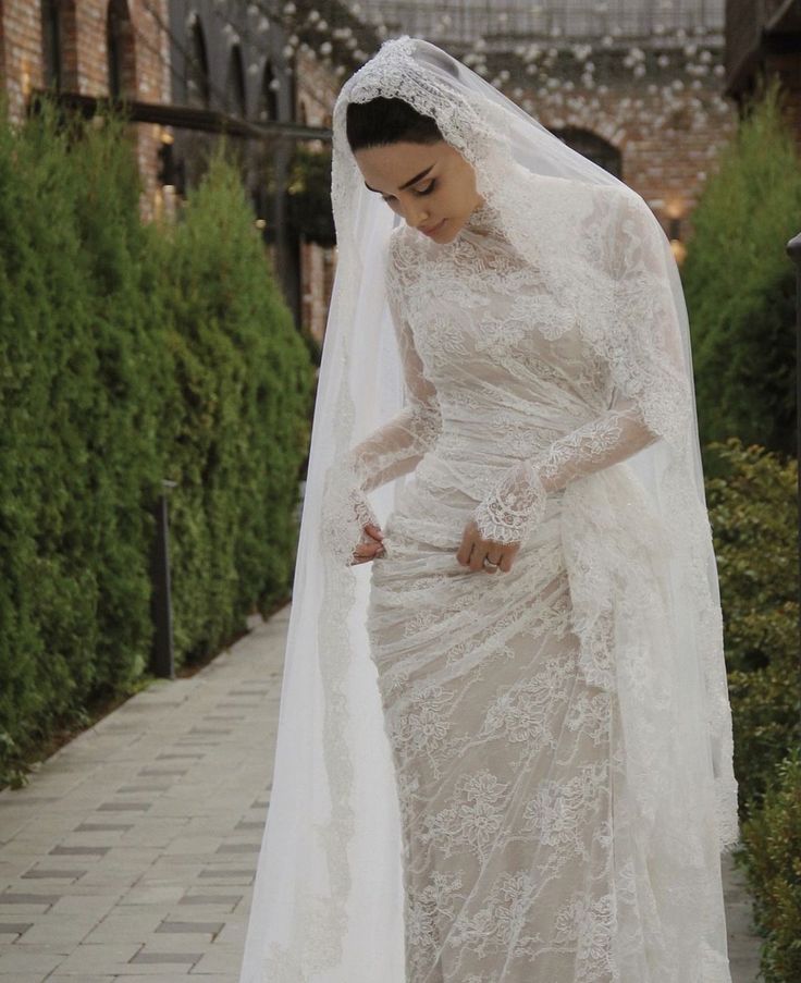 a woman in a wedding dress and veil is walking down the street with her hand on her hip