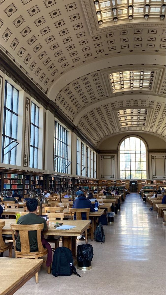 the inside of a library with tables, chairs and bookshelves filled with people