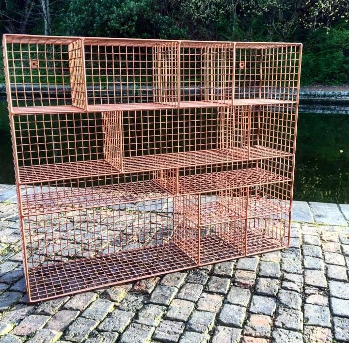 four metal cages sitting on top of a brick walkway next to water and trees in the background