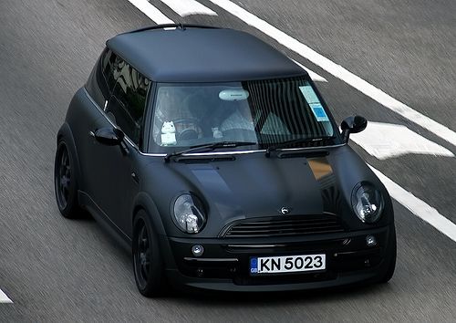 a small black car driving down the road