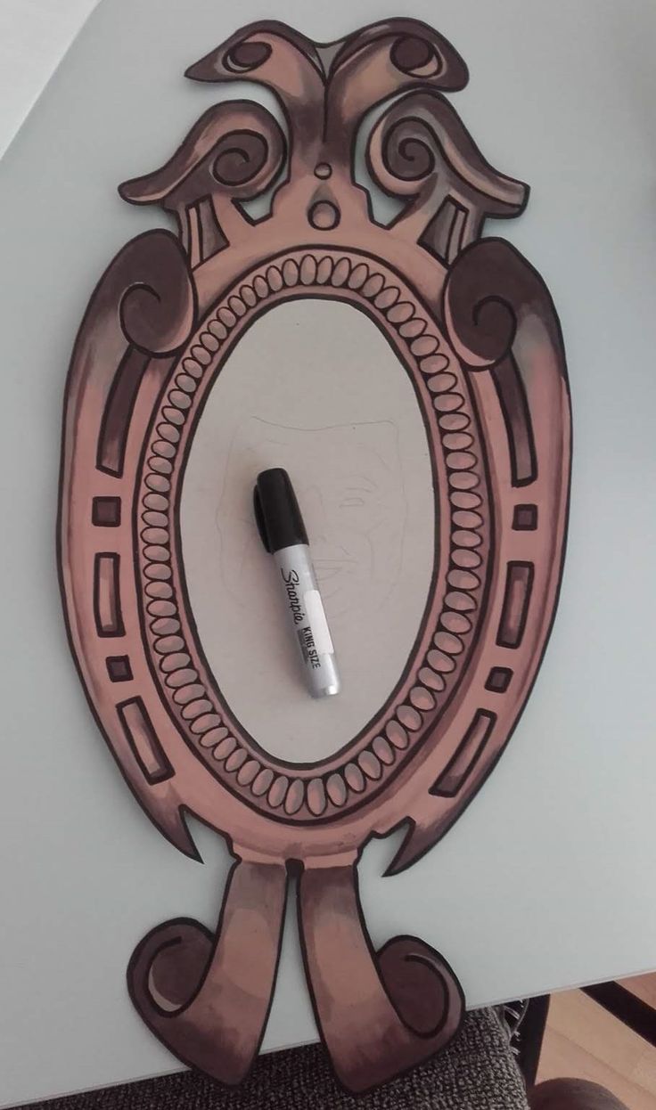 a mirror with a black marker on it next to a brown and white wall hanging