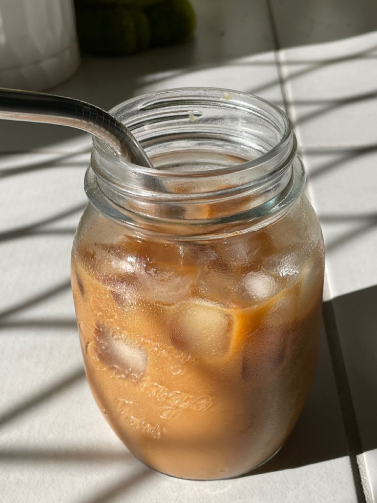 a glass jar filled with liquid and ice sitting on top of a white tile floor